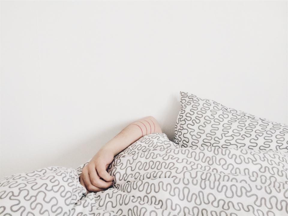 The arm of a sleeping person on a duvet