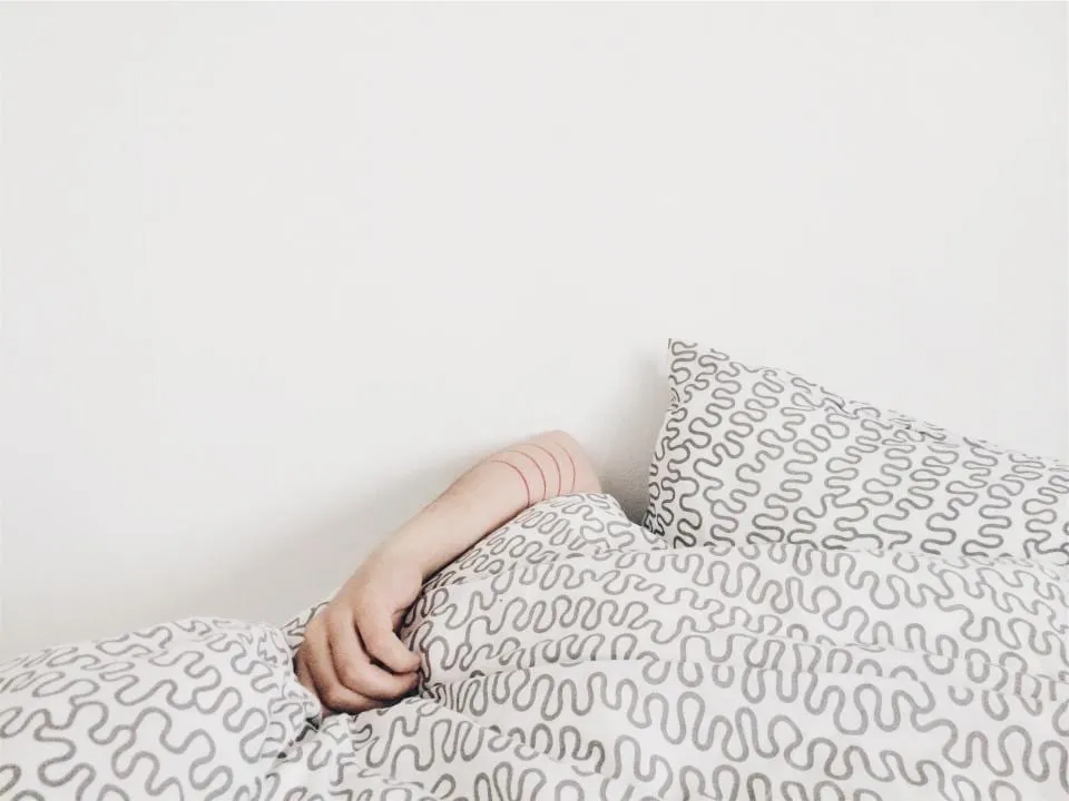 The arm of a sleeping person on a duvet