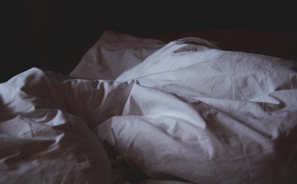 Rumpled bedding in a dark bedroom